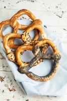 pretzels macios caseiros preparados na hora. diferentes tipos de bagels assados com sementes em um fundo preto. foto