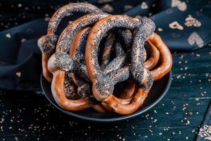 pretzels macios caseiros preparados na hora. diferentes tipos de bagels assados com sementes em um fundo preto. foto