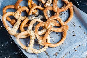 pretzels macios caseiros preparados na hora. diferentes tipos de bagels assados com sementes em um fundo preto. foto