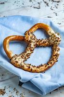 pretzels macios caseiros preparados na hora. diferentes tipos de bagels assados com sementes em um fundo preto. foto