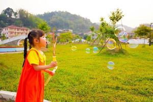 linda menina usa roupa amarelo-laranja, roupa gokowa ou mugunghwa jogando bolha em um parque público. meninas e vestido de moda adolescente. foto