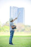 um menino meio índio tailandês usando um capacete segura uma planta e esperando que no futuro seja um engenheiro para construir prédios foto