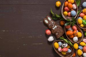 fundo de conceito de caça de páscoa com ovos de chocolate e coelho no espaço de cópia de mesa de madeira foto