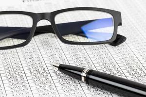 análise de relatório financeiro com caneta e óculos foto