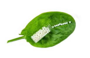 homeopatia - um conceito de homeopatia com medicamento homeopático em folhas verdes foto