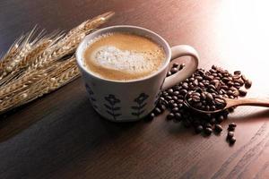café com leite quente com grãos de café na mesa de madeira foto
