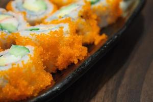 rolo de sushi, linha de sushi de rolo de maki califórnia com caviar na chapa preta foto