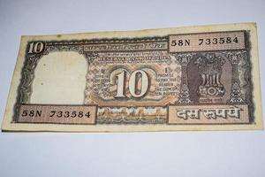 rara nota de moeda indiana de dez rúpias em fundo branco, governo da índia nota de dez rúpias antiga moeda indiana, velha nota de moeda indiana em cima da mesa foto