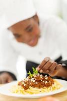 espaguete de guarnição de cozinheiro africano feminino foto