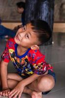 menino asiático indefinido sorrindo e olhando para a câmera dentro de casa, foto