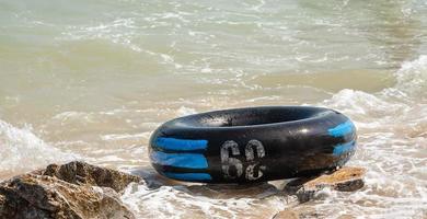 close-up de anel inflável preto ou anel de borracha na rocha na praia do mar foto