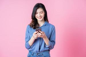 imagem de jovem empresária asiática usando smartphone em fundo rosa foto