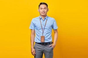 homem de negócios jovem sorridente na camisa azul clássica parecendo confiante isolado sobre fundo amarelo. conceito de negócio de riqueza de carreira de realização foto