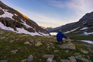 uma pessoa assistindo o nascer do sol no alto dos Alpes