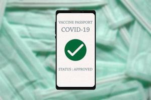 passaporte de vacina covid-19 aprovado pelo teste de aplicativo para smartphone em fundo de máscaras protetoras desfocadas. campanha de vacinação e novo conceito de estilo de vida de prevenção normal. foto