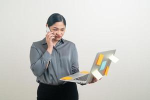 Mulher de negócios asiáticos falando ao telefone com a mão segurando um laptop foto