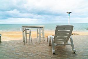 mesa e cadeira ao ar livre do pátio na praia com fundo de praia do mar foto