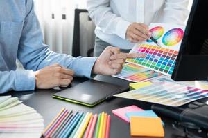 equipe de designer gráfico trabalhando em web design usando amostras de cores editando obras de arte usando tablet e uma caneta em mesas no escritório criativo