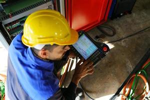 engenheiro industrial ou trabalhador usando um capacete em pé em uma fábrica industrial pesada. a manutenção procurando trabalhar em máquinas industriais e verificar a configuração do sistema de segurança na fábrica. foto