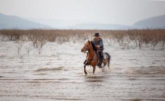 cowboy a cavalo contra um belo pôr do sol, cowboy e cavalo na primeira luz, montanha, rio e estilo de vida com fundo de luz natural foto