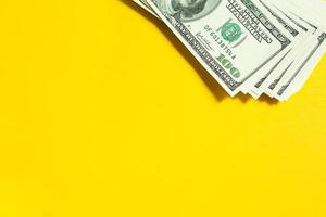 uma pilha de 100 notas em um fundo amarelo. negócio de conceito, finanças, investimento, pagamento em dinheiro, poupança e riqueza. espaço de cópia foto