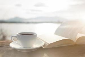 xícara de café e livro em uma mesa de madeira foto