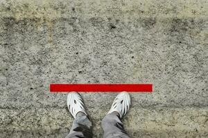 de cima para baixo dos pés fique na linha vermelha no piso. conceito de espaço público praticando distanciamento social. foto