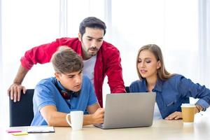 grupo diversificado de jovens empresários discutindo um projeto de trabalho enquanto estão sentados juntos em uma mesa em um escritório moderno. conceito de coworking foto