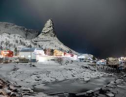 montanha de neve na vila de pescadores com geleira à noite foto