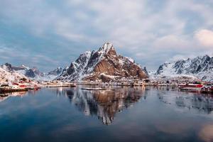 reflexão de montanha no oceano ártico com vila piscatória norueguesa foto