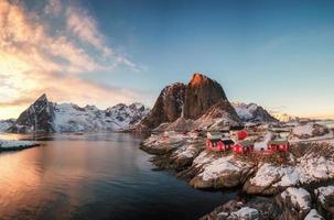 vila de pescadores de casa vermelha com montanha de neve ao pôr do sol foto