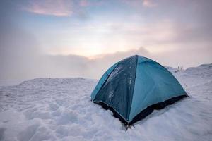 barraca azul de acampamento na colina nevada no nevoeiro foto