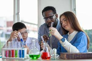 alunos misturam produtos químicos em béqueres. professor entusiasmado explica química para crianças, estudante de química mostrando um novo experimento para a aula de ciências do professor foto