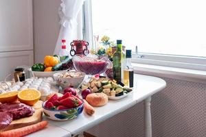 ingrediente com muitos alimentos, legumes, frutas se preparando para o jantar na mesa de jantar foto