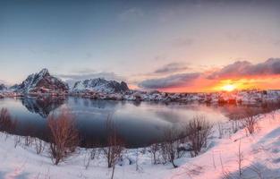 nascer do sol na vila reine com reflexo de montanha de neve no litoral nas ilhas lofoten foto