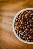 grãos de café na xícara em fundo de madeira grunge foto