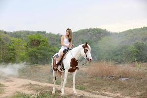 jovem e bonita com seu cavalo na luz do sol à noite. fotografia ao ar livre com garota modelo de moda. humor de estilo de vida foto