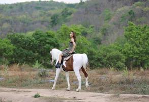 jovem e bonita com seu cavalo na luz do sol à noite. fotografia ao ar livre com garota modelo de moda. humor de estilo de vida foto