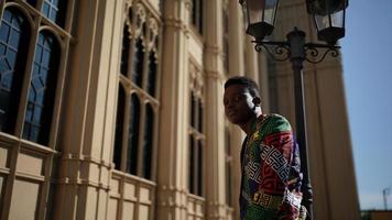 homem afro-americano se divertindo andando no centro da cidade - cara jovem feliz aproveitando o tempo um pôr do sol ao ar livre - estilo de vida da geração milenar e conceito de atitude positiva das pessoas foto