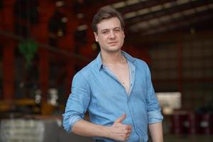 retrato de homem bonito na camisa azul em pé ao ar livre. foto