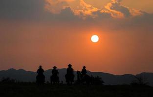 silhueta cowboy a cavalo contra um belo pôr do sol, cowboy e cavalo na primeira luz, montanha, rio e estilo de vida com fundo de luz natural foto