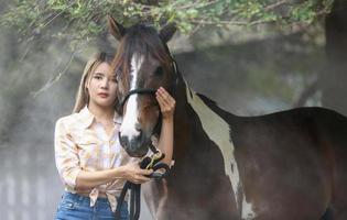 jovem e bonita com seu cavalo na luz do sol à noite. fotografia ao ar livre com garota modelo de moda. humor de estilo de vida foto