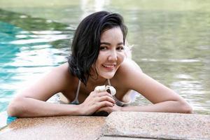 retrato de biquíni jovem sorridente em pé na piscina foto