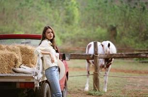 jovem e bonita com seu cavalo na luz do sol à noite. fotografia ao ar livre com garota modelo de moda. humor de estilo de vida foto