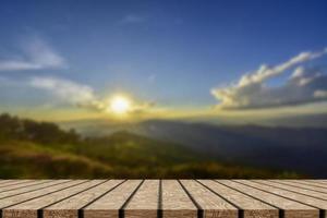 mesa de madeira e borrão de beleza, céu pôr do sol e montanhas como pano de fundo. foto