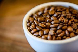 grãos de café na xícara em fundo de madeira grunge foto