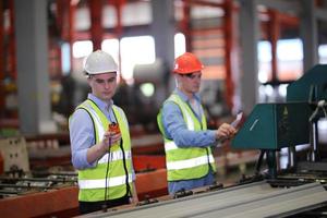 engenheiro industrial de homens usando um capacete de segurança em pé em uma fábrica industrial pesada. a manutenção procurando trabalhar em máquinas industriais e verificar a configuração do sistema de segurança na fábrica. foto