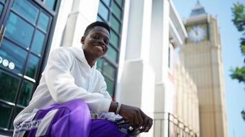 homem afro-americano se divertindo andando no centro da cidade - cara jovem feliz aproveitando o tempo um pôr do sol ao ar livre - estilo de vida da geração milenar e conceito de atitude positiva das pessoas foto