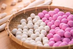 uma mulher asiática está fazendo tang yuan, yuan xiao, bolinhos de arroz de comida tradicional chinesa em vermelho e branco para o ano novo lunar, festival de inverno, close-up. foto