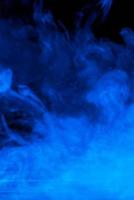 imagem conceitual de fumaça azul isolada em fundo preto escuro e mesa de madeira. foto
